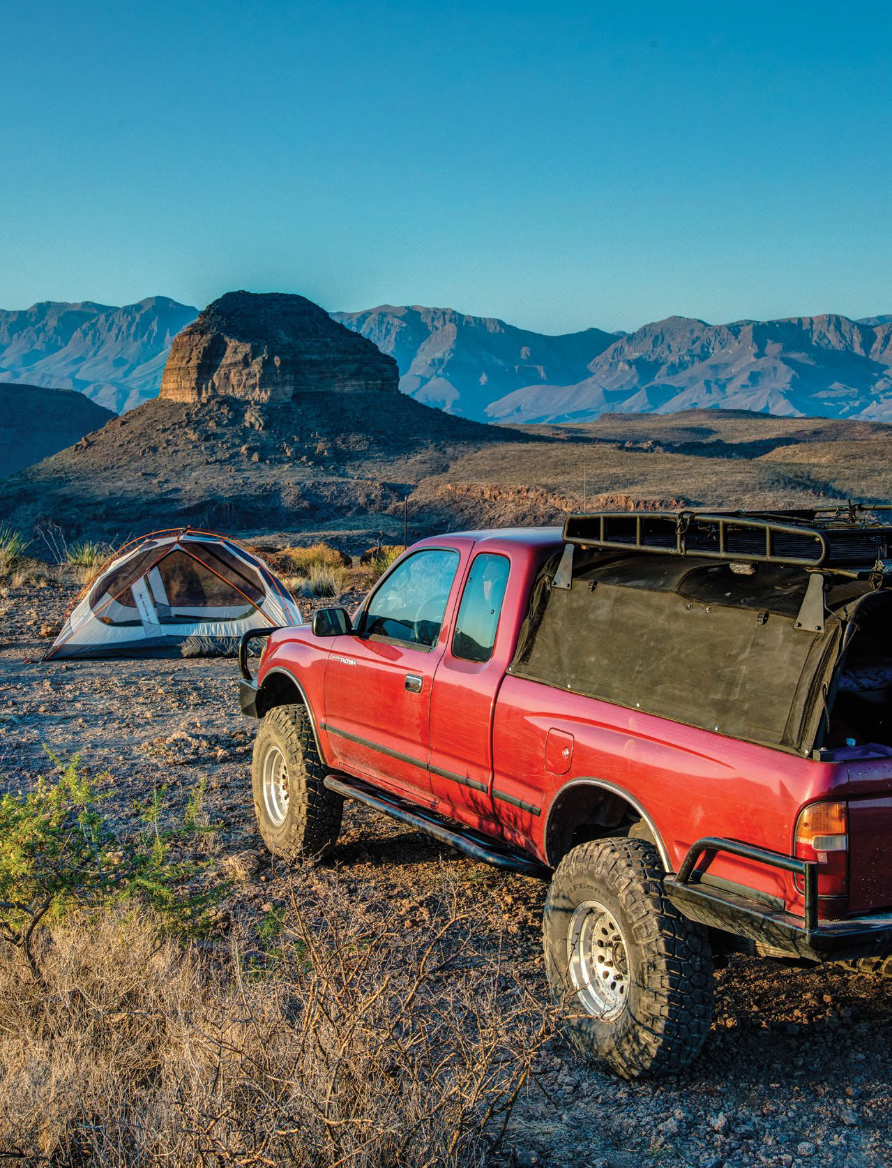 A red Toyota Tacoma with a view of the desert